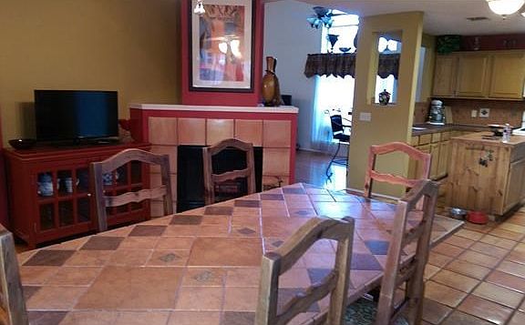 Dining room next to the open kitchen with island and a wood burning fireplace.