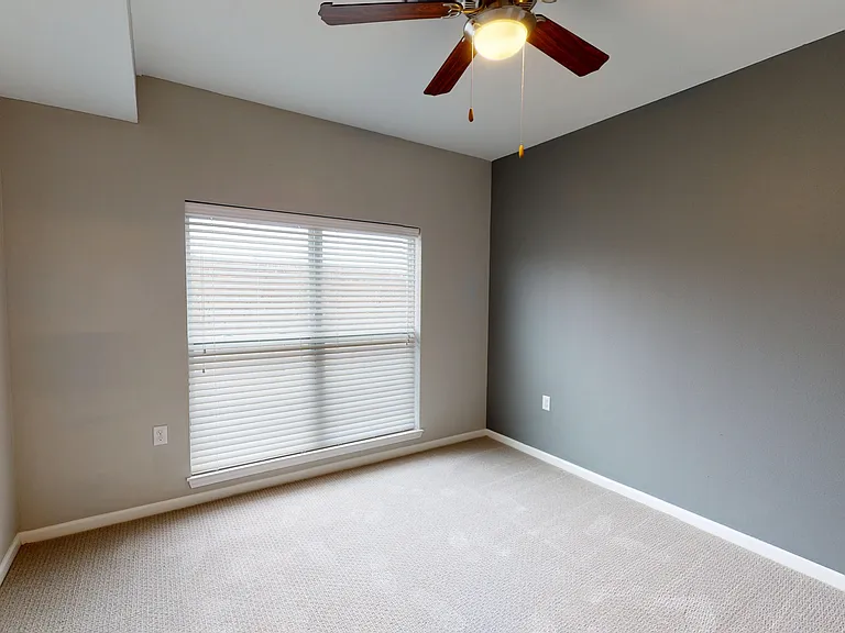 The second bedroom of The Hickory floor plan features a large window, ceiling fan, accent wall, and a large closet. The second bedroom of The Hickory floor plan features a large window, ceiling fan, accent wall, and a large closet.