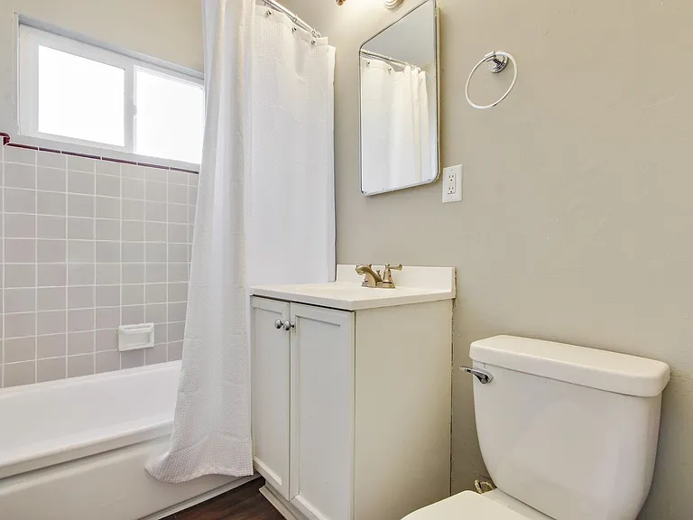 Bathroom with Single round vanity, white cabinet, tub and shower combo with light gray wall tiles