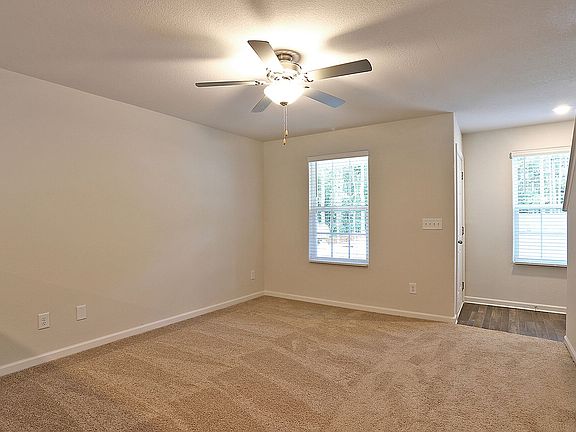 Spacious living room has ceiling fan and several windows