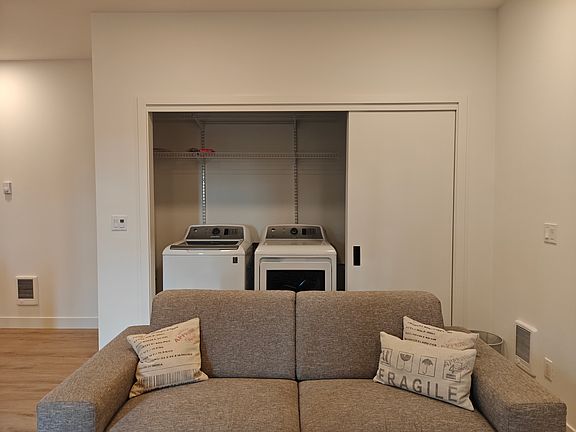 Living room couch with W&D and shelving in the closet.