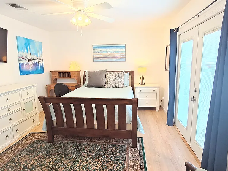 Fourth hall bedroom/primary bedroom. Doors lead to back patio. Master bath behind viewer.