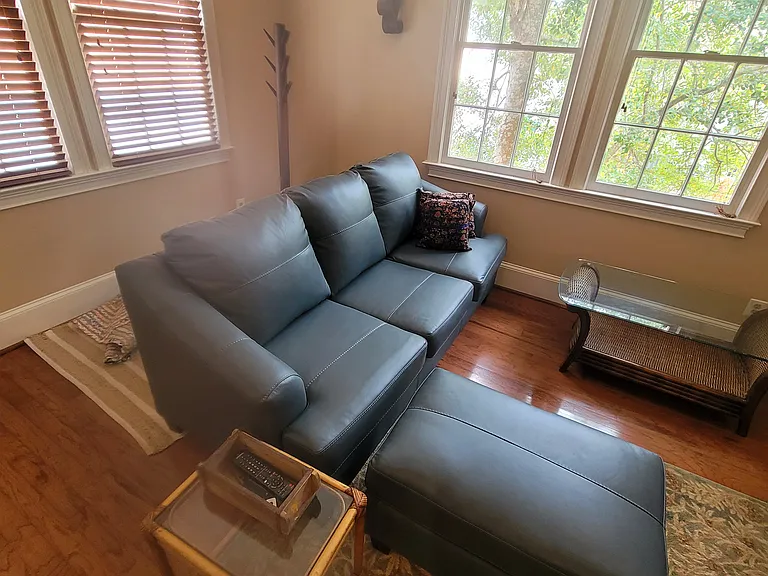 Leather sofa with ottoman. Hardwood floors.