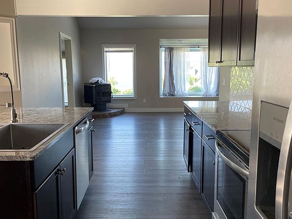 From laundry hallway looking through kitchen to living room with pellet stove.