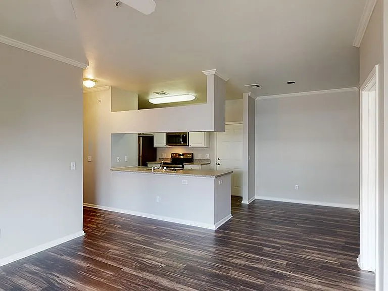 Apartment kitchen with stainless steel appliances in select homes, dining and living room with wood-style flooring.