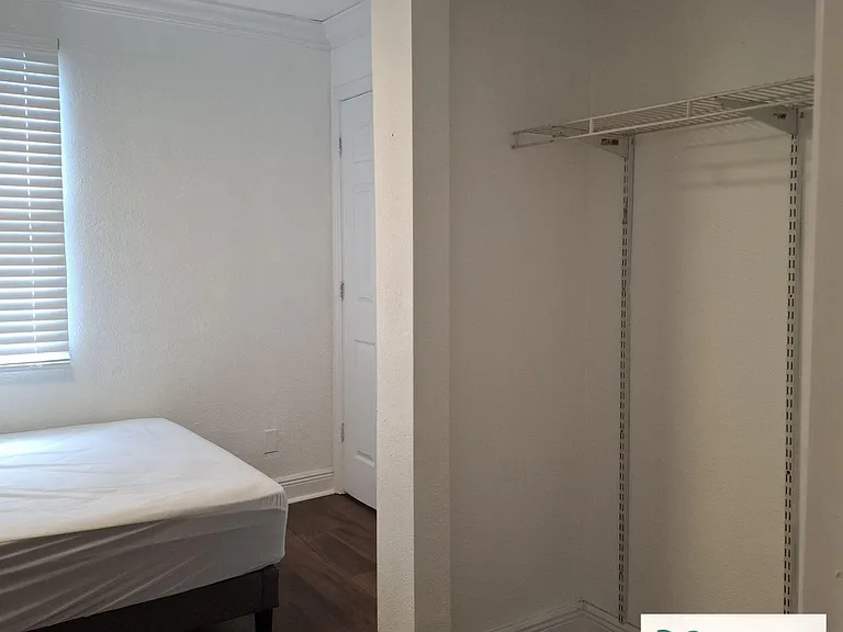 Private bedroom with a window for natural light, durable flooring, and an open closet with shelving for easy storage.