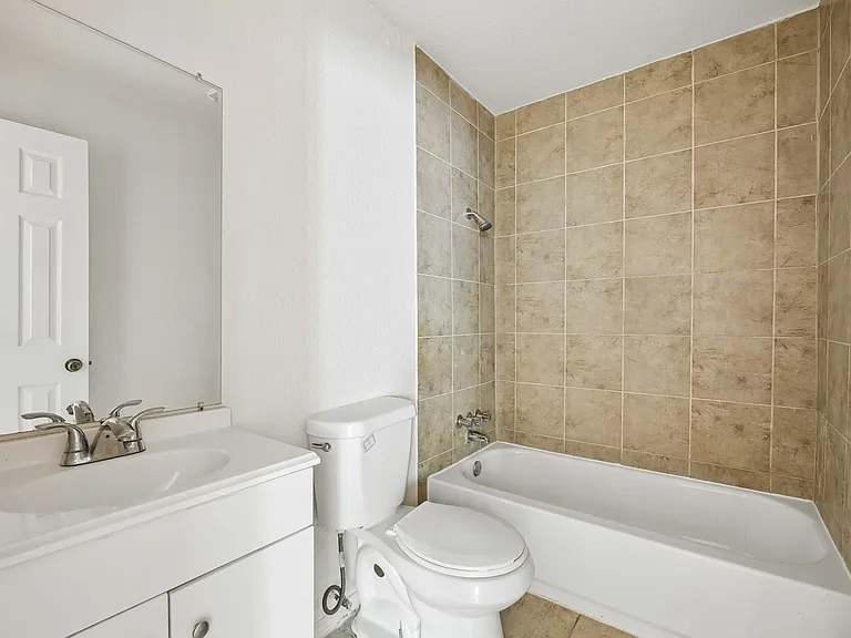 Bathroom featuring a white vanity with an integrated sink, a chrome faucet, and a wall-mounted mirror
