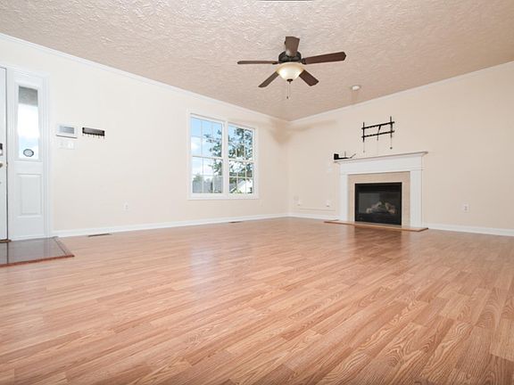 Living Room with brand new laminate flooring. TV wallmount stays and can support up to an 80 inch TV. Gas fireplace (propane tank hookup outside through the wall and hidden by bushes).