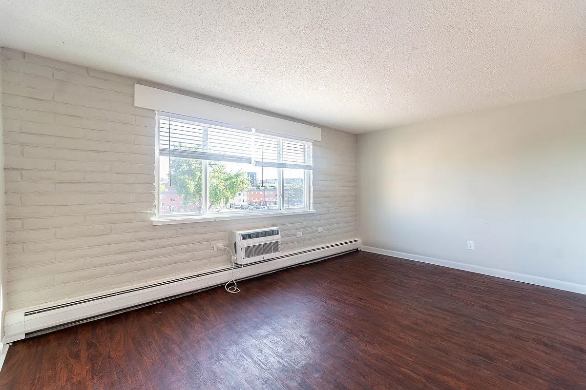 Bright living area with large window and elegant hardwood floors, offering a welcoming and spacious environment. - Creekside