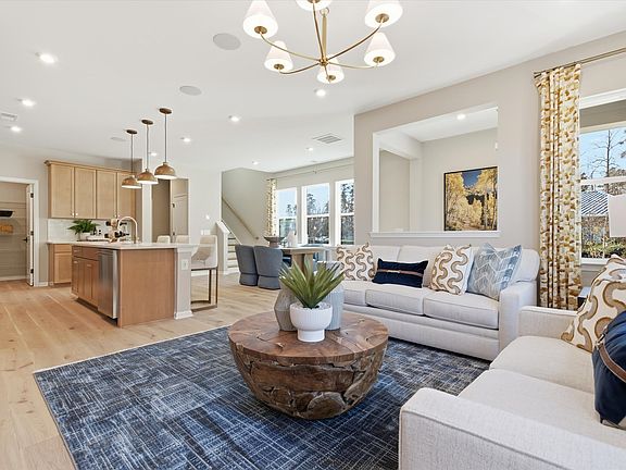 A cozy and well-furnished living room with a modern chandelier, a wooden coffee table, and a comfort