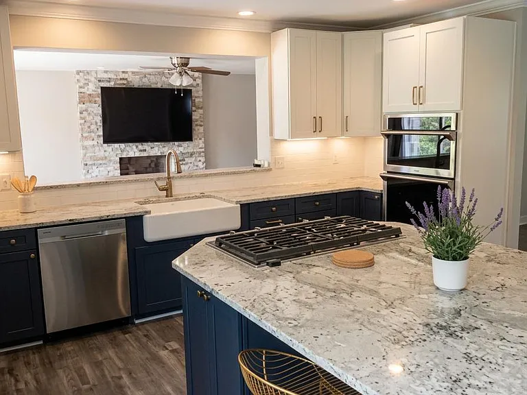 Spacious kitchen with large island seating, gas cooktop, farmhouse sink, and double wall ovens, open to the living area.