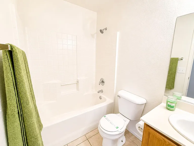 Full bathroom with tub/shower combo, tile surround, and a single-sink vanity with mirror and towel storage.