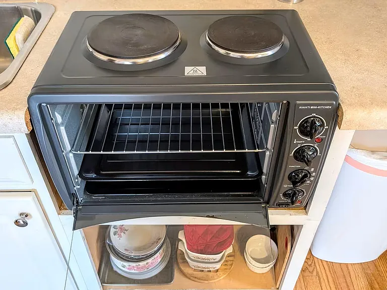 Kitchen counter area with a compact electric cooktop and toaster-oven for convenient everyday meal prep.