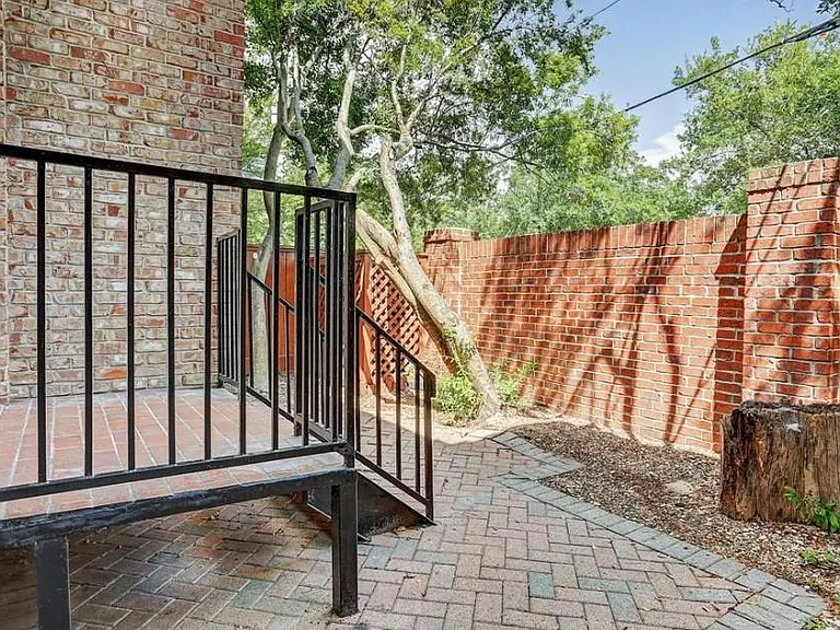 Backyard patio space with brick fence and mature trees