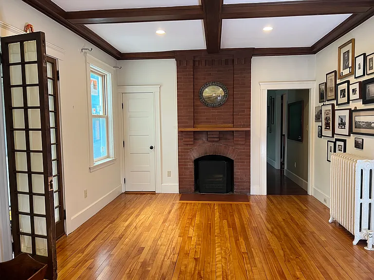 Living room with beamed ceiling, fireplace, french doors to sun porch, and door to 1/2 bath.