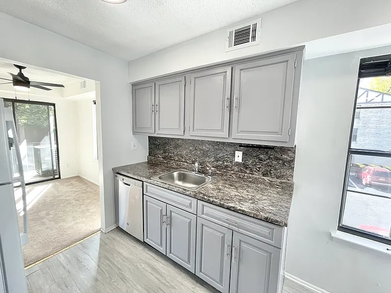 Stainless dishwasher & view into dining area w/private terrace
