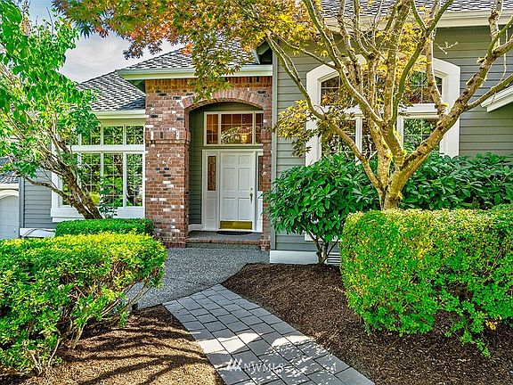 Mature shade trees and winding stone paths add to the curb appeal.