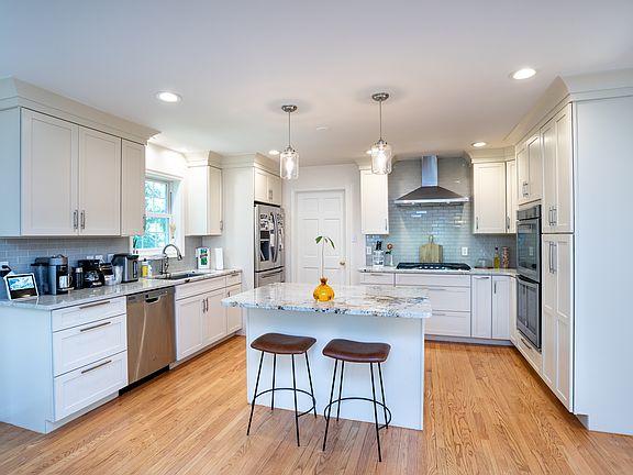 Beautifully updated kitchen boasting dual ovens, a gas range with a stainless hood, granite countertops, ample cabinet space, a breakfast nook, and an island with room for seating.