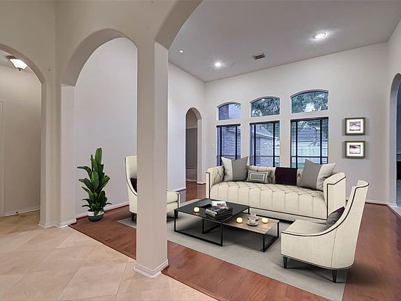 Arches and hardwood floors define the living room which has plenty of natural light through the set of floor to nearly ceiling windows.