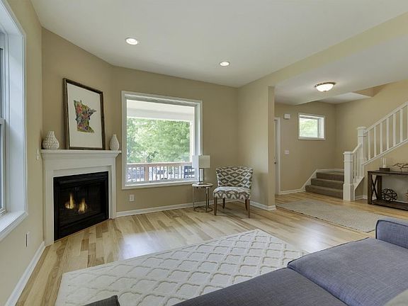Front living room with gas fireplace, hardwood floors, large picture window lets in natural light.