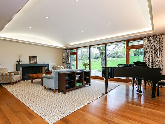 The living room with wood burning fireplace is a magnificent entertaining room with floor to ceiling windows overlooking the expansive patio and rolling lawns.