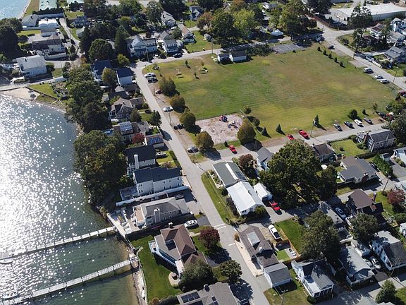 The house is bottom center of the picture with the wite car and fenced in yard. Top center is the park with a playground, basketball court, bocce court, baseball field, and open parking.