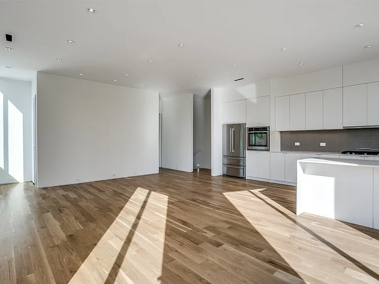 Contemporary kitchen featuring white flat-panel cabinetry, a stainless steel refrigerator, an integrated wall oven, and a mosaic tile backsplash