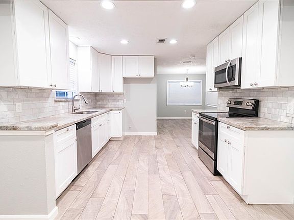 This spacious kitchen features, high ceilings, white cabinets, beautiful counter tops, matching appliances, modern tile back splash, and recessed lighting!