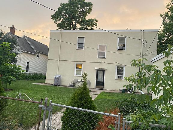 Fenced in backyard with seating area and gas grill.