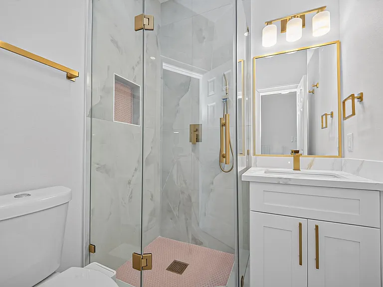 Updated bathroom with a glass-enclosed shower, tiled surround, and a vanity with storage and a framed mirror.