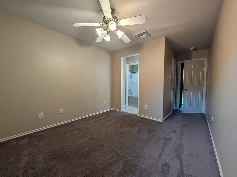 Comfortable secondary bedroom featuring ceiling fan, plush carpet, and convenient access through to the shared Jack-and-Jill bath layout.