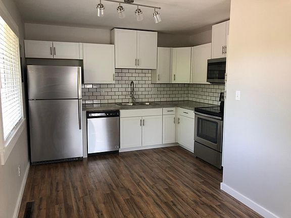 Updated kitchen with stainless steel appliances, concrete countertop, and subway tile backsplash.