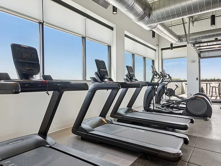 Stay active with a bright, modern fitness studio featuring treadmills, cardio machines, and rooftop-level views.