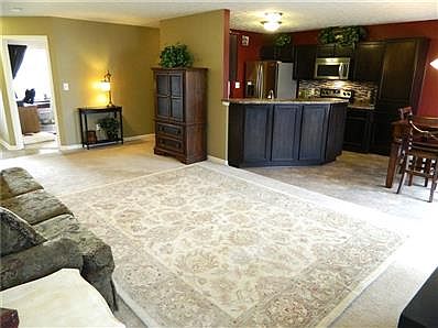 Living room looks into open kitchen on right, office in background.