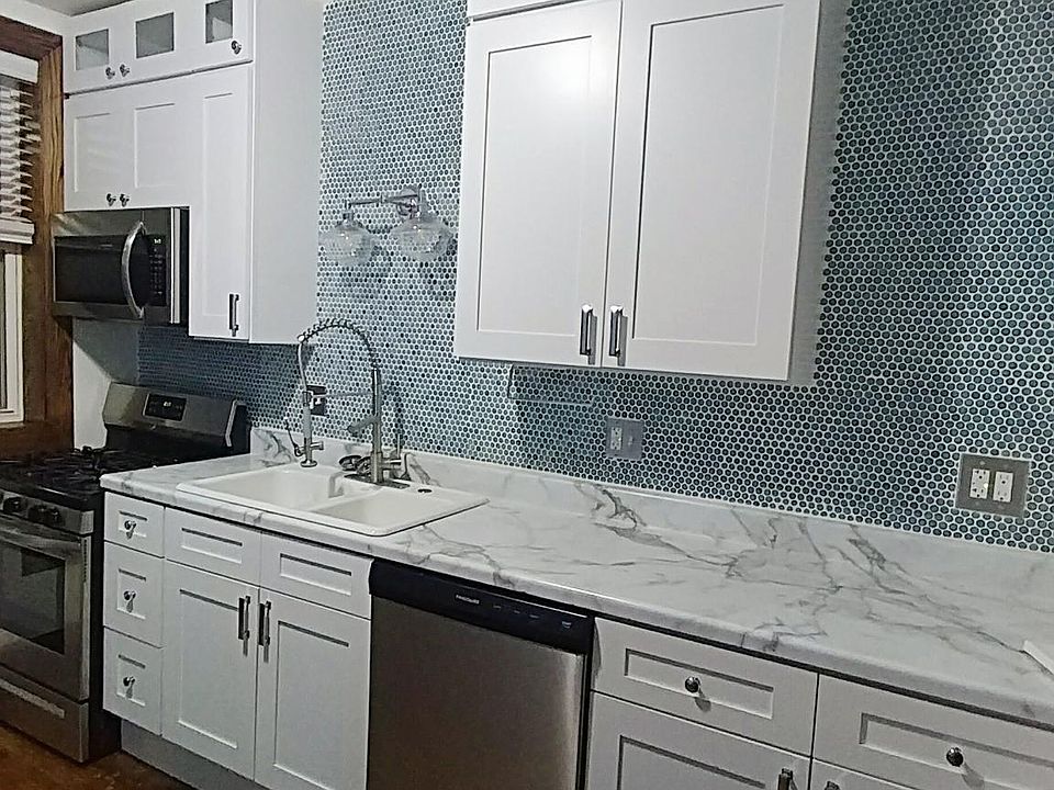 Kitchen with clean white cabinets. Porcelain penny tile to the ceiling.