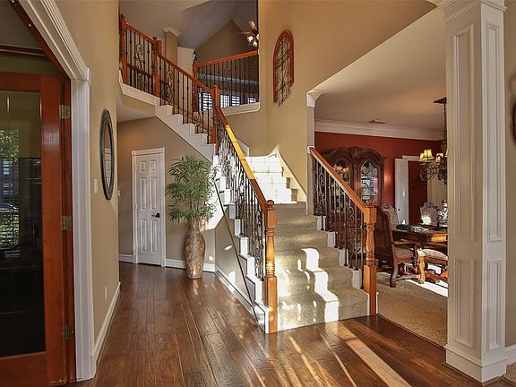 Inviting entry with hand scraped wood floors and iron stair case.