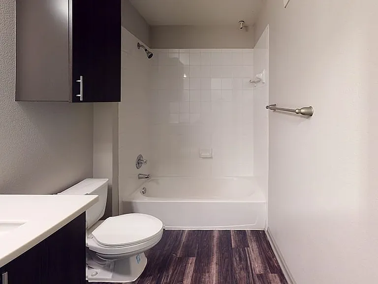 Apartment bathroom with large soaking tub and wood-style flooring.