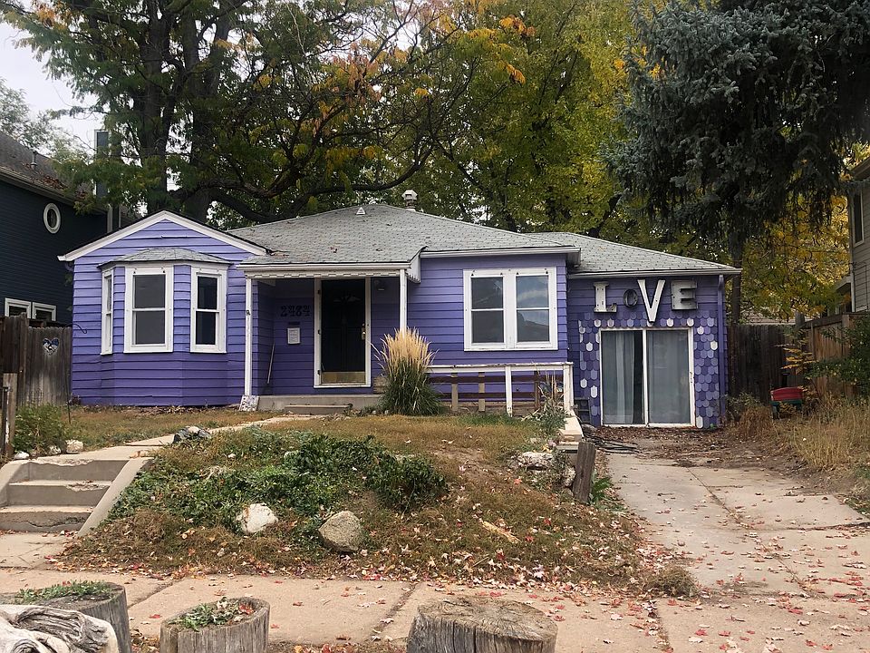 Front of DU/University Park iconic Purple Love house. Drive way for off street parking (2 cars) seen on the right. Sliding glass doors below the LOVE sign are 1 entrance to 3rd bedroom.