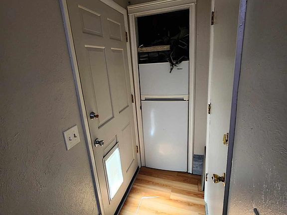 Internal photo of bottom of stairs. Front door to the left, garage door to the right. We do have the door to the small closet where we put our drink fridge.