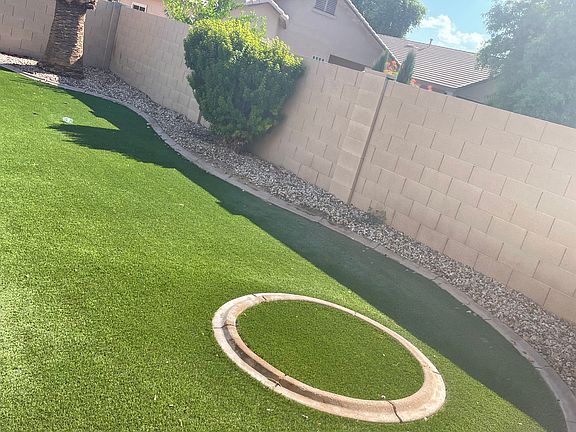 Large backyard with artificial turf and room to plant a large tree in the circular area for additional shade