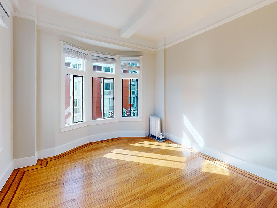 Bright, spacious room featuring hardwood floors and bay windows, with light streaming in