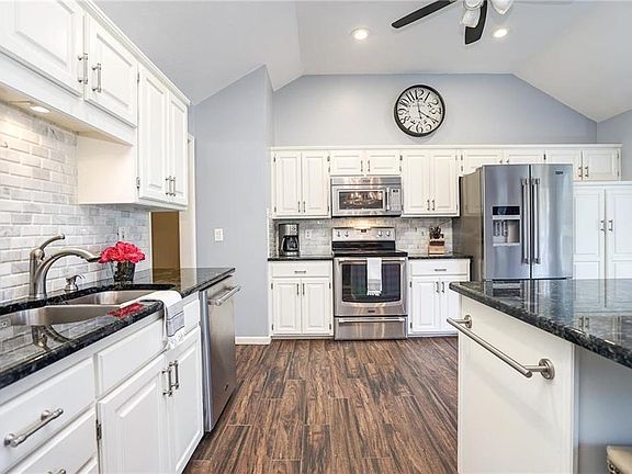 Beautiful updated kitchen with granite counter tops, expanded island, updated lighting fixtures, newer kitchen appliances and tiled flooring. Kitchen includes pantry, vaulted ceiling and ceiling fan. Open to eat-in dining.