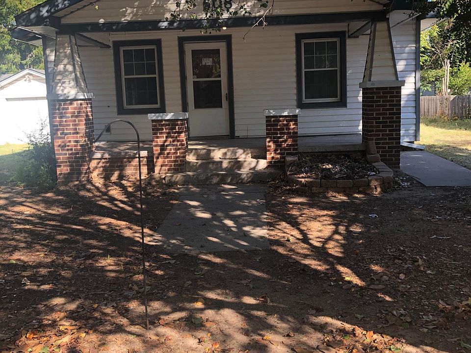 Covered front porch with room for outdoor seating. There is an electrical outlet to the left.