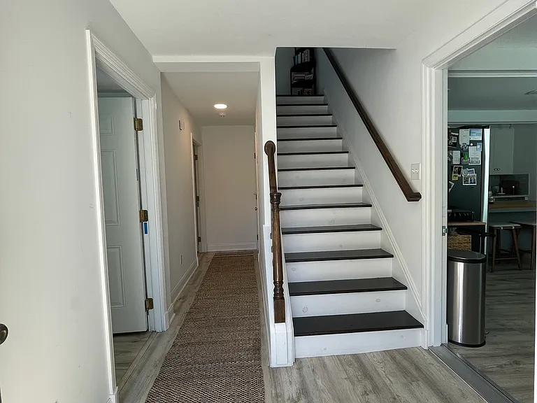 First floor hall with primary bedroom, first floor full bath and stairs leading to 2nd level