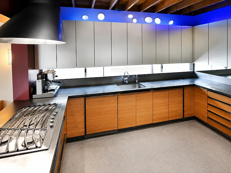 Gourmet kitchen facing north. Operable slot window under cupboards. Blue led lights above cupboards with oval light tubes. Black terrazzo countertops with illuminating glass imbeds.