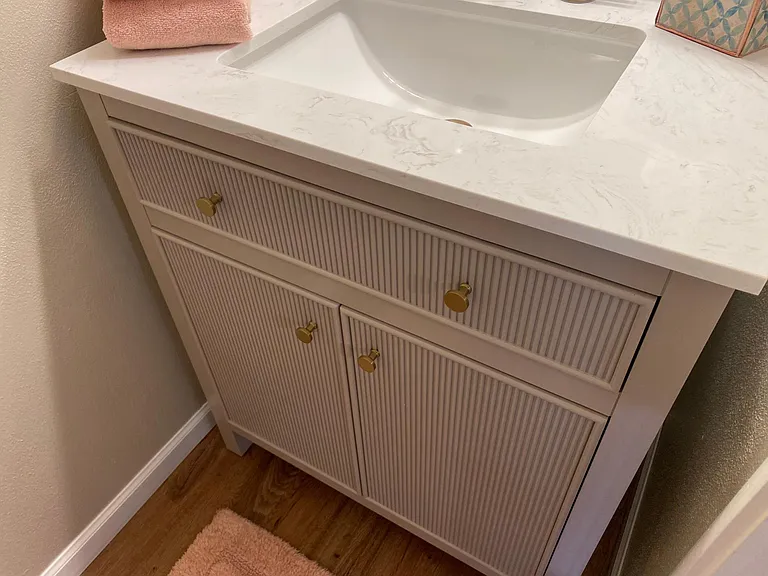 Downstairs toilet room has new flooring, hi-boy elongated bowl toilet and beautiful new greige vanity with brushed brass accents on engineered marble top_