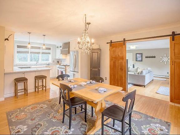 Kitchen with small dining area looks in to great room with large screen TV.