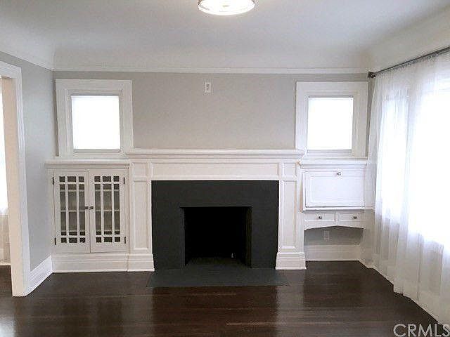 Living room with decorative fireplace and mantlepiece and beautiful original craftsman built-in bookshelf and desk.