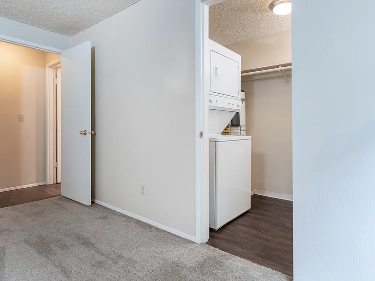 Bedroom with convenient in-unit laundry, featuring a stacked washer and dryer in a walk-in closet. Bedroom with convenient in-unit laundry, featuring a stacked washer and dryer in a walk-in closet.