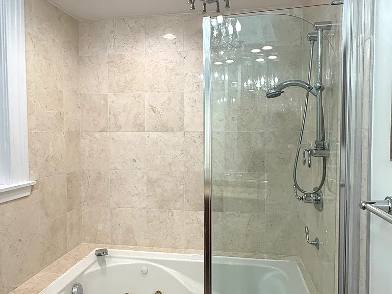 Travertine bathroom with whirlpool, spider overhead shower and handheld shower
